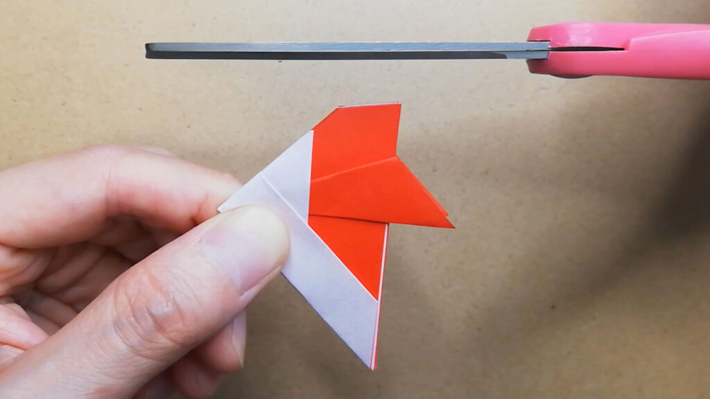 赤色の折り紙をハサミで切る